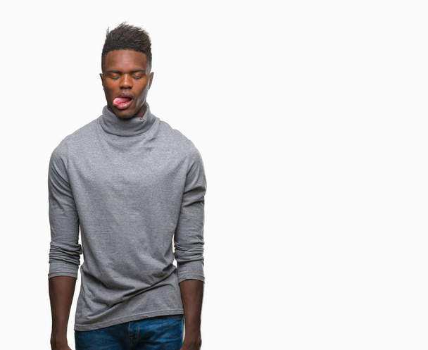 Młody człowiek african american na białym tle trzymanie języka out z wyrażenie zabawny zadowolony. Emocja koncepcja. - Zdjęcie, obraz