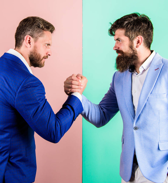 Business partners competitors office colleagues tense faces ready to compete in arm wrestling. Hostile or argumentative situation between opposing colleagues. Business competition and confrontation - 写真・画像