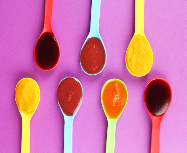 Baby puree in spoons on purple background - Photo, Image