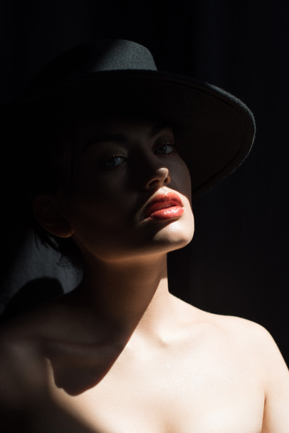 bella ragazza elegante in cappello di feltro nero in posa nel buio
 - Foto, immagini