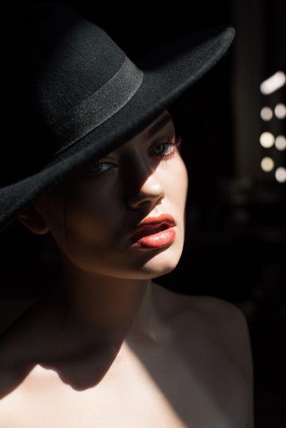 όμορφο κορίτσι με μακιγιάζ θέτοντας σε μαύρο καπέλο από τσόχα  - Φωτογραφία, εικόνα