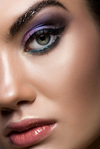 Close-up van het jonge model poseren met glitter make-up camera kijken - Foto, afbeelding