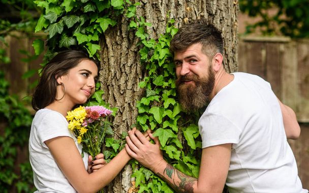 Pleasant date in nature environment. Couple in love romantic date walk nature tree background. Couple in love lean on trunk with ivy. United with nature. Man bearded hipster holds hand girlfriend - Foto, Bild