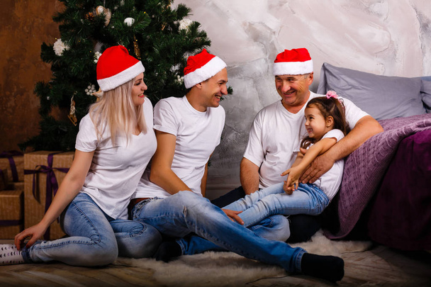 Happy family in jeans sitting near xmas tree in anticipation of the new year - Zdjęcie, obraz
