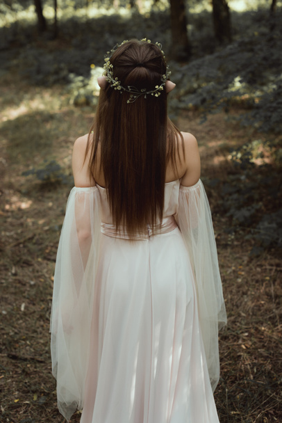 Задний вид мистического эльфа в элегантном платье и цветочный венок в лесу
 - Фото, изображение