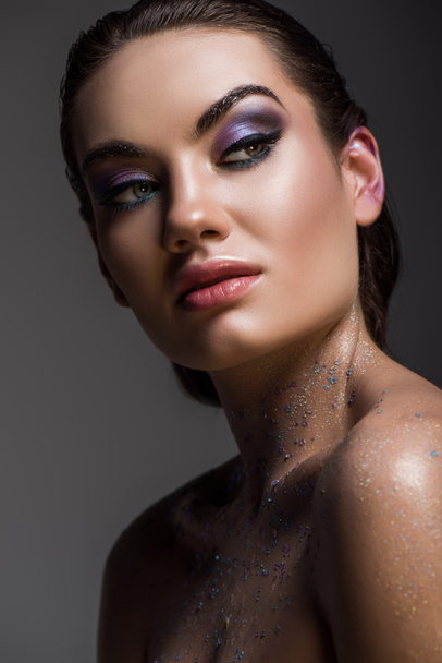 glamorous girl posing with glitter on body for fashion shoot, isolated on grey - 写真・画像