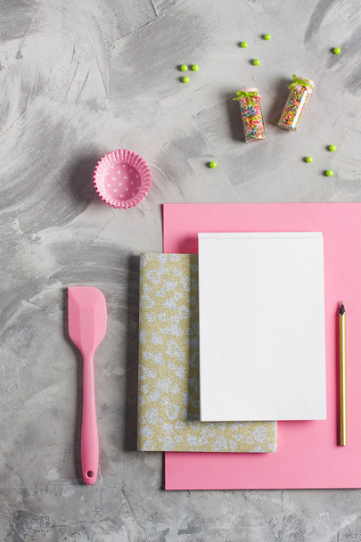 Pink paper gold notebook white copy space for text or recipe, pencil, colored sprinkling, cupcake molds, kitchen tools silicone spatula. Concept cooking baking for kids, flat lay background. - Photo, Image