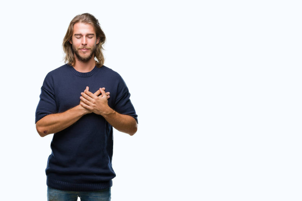 Young handsome man with long hair wearing winter sweater over isolated background smiling with hands on chest with closed eyes and grateful gesture on face. Health concept. - Foto, imagen