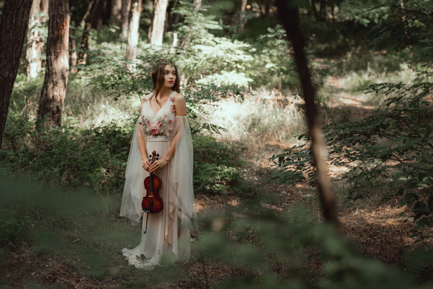 mystic elf in elegant dress holding violin in beautiful forest - Photo, Image