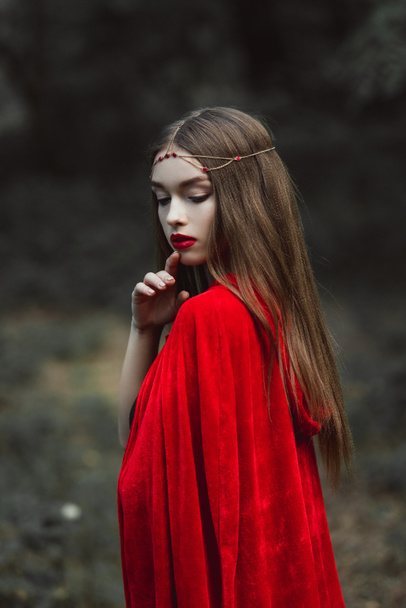 Мистическая девушка в красном плаще и элегантный венок в лесу
 - Фото, изображение