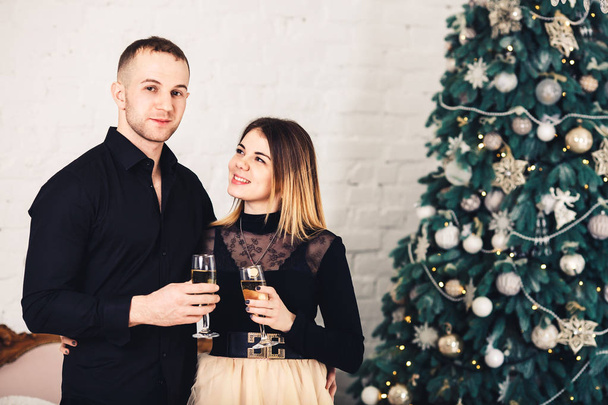 любящая пара в стильной одежде с бокалами вина на Рождество
. - Фото, изображение