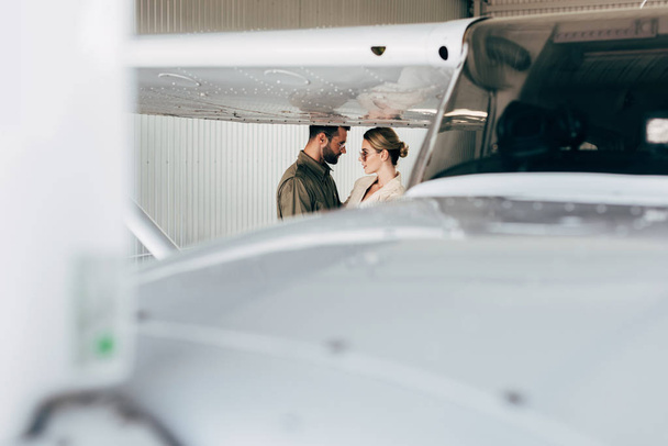 selective focus of stylish couple looking at each other near plane  - Foto, Imagen