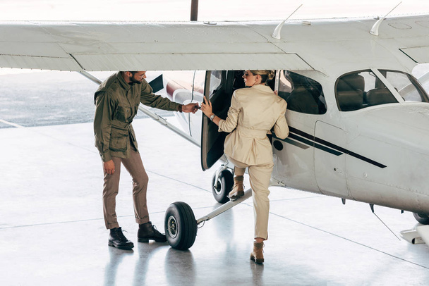 tyylikäs nuori mies avaa oven tyttöystävä, kun hän lennolle lentokoneessa
  - Valokuva, kuva