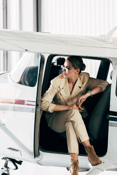 jeune femme à la mode dans les lunettes de soleil et veste assis dans l'avion
  - Photo, image