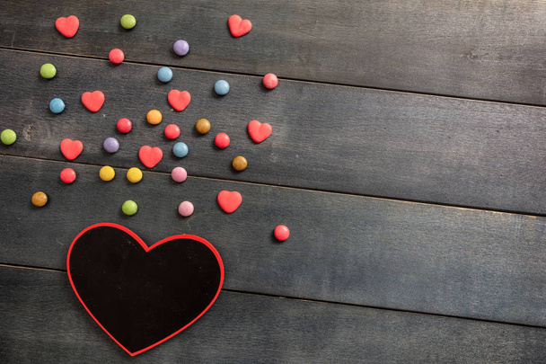 Романтичне кохання. Дошка у формі серця та цукерки на дерев'яному фоні, вид зверху та місце для тексту
. - Фото, зображення