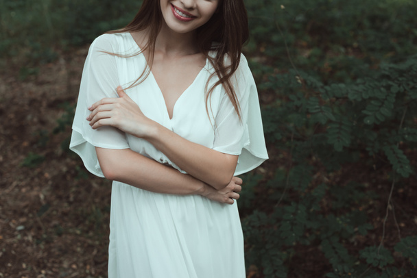 cropped view of smiling girl posing in white dress  - Zdjęcie, obraz