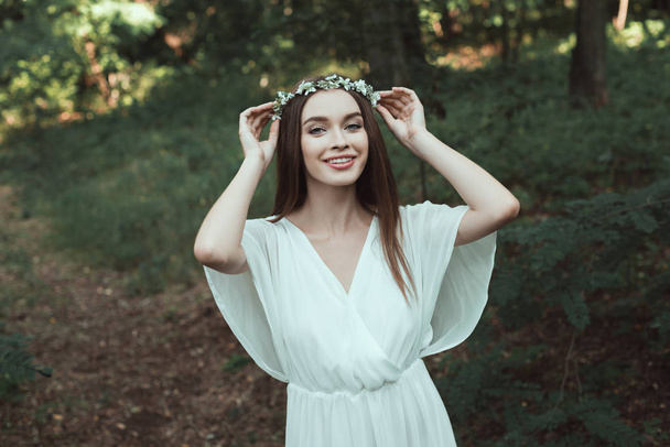 beautiful happy girl posing in floral wreath in forest - Fotografie, Obrázek