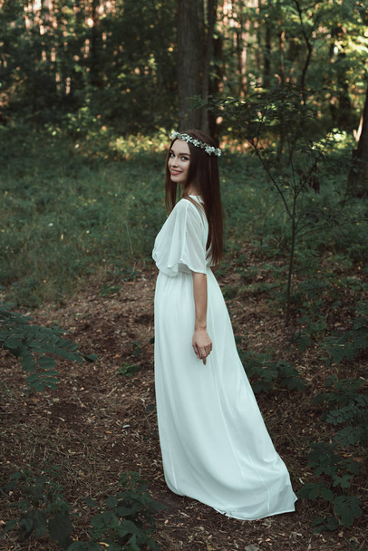 Atrakcyjna dziewczyna uśmiechający się w białą suknię spaceru w lesie - Zdjęcie, obraz