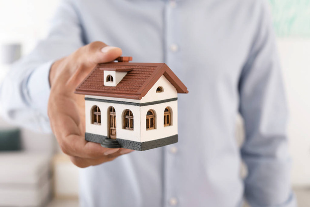 Real estate agent holding house model, closeup - Фото, изображение