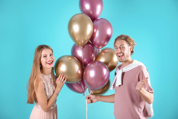 Young couple with air balloons on color background - Foto, afbeelding