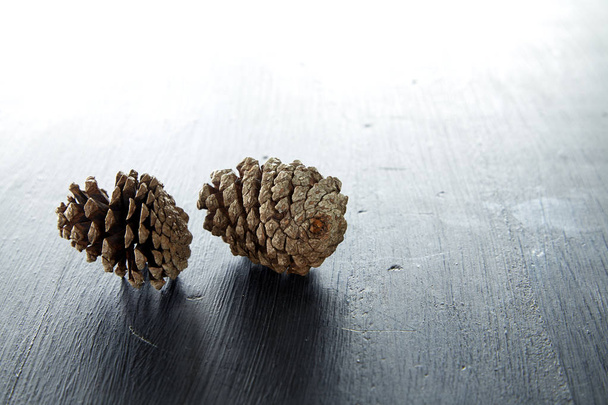 Primer plano de dos cono de pino sobre una mesa de madera fondo natural
 - Foto, imagen