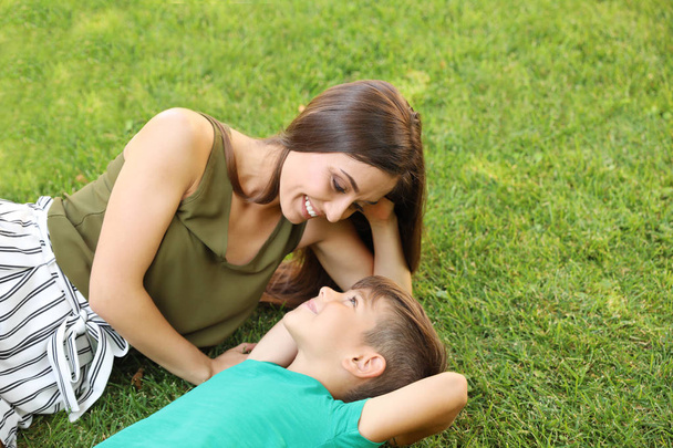 Mother with her cute child on green grass in park. Happy family - Zdjęcie, obraz