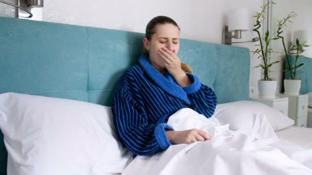 hasta kadın yatakta yatan ve sıcaklık termometre ile ölçerek bornoz 4 k görüntüleri - Video, Çekim