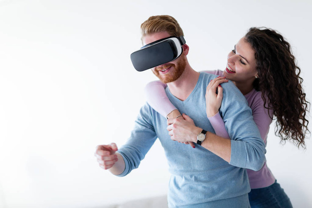 Young happy couple playing games with virtual reality headset together - Zdjęcie, obraz