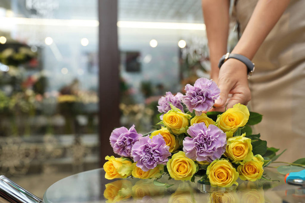 Женщина-флорист держит красивый цветок в магазине
 - Фото, изображение
