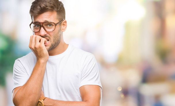 Young handsome man wearing glasses over isolated background looking stressed and nervous with hands on mouth biting nails. Anxiety problem. - Photo, Image