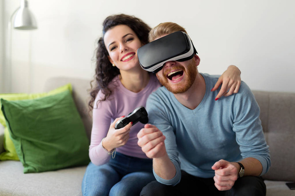 Happy young couple playing video games with virtual reality headsets at home - Valokuva, kuva