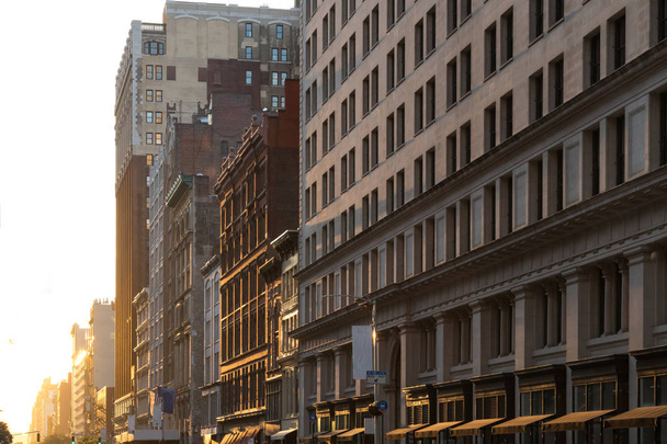 マンハッタンの23丁目沿いの建物に夕焼けの暖かい光が輝く - 写真・画像