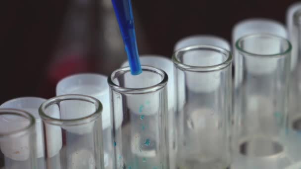 V laboratoři vědec s pipetou analyzuje modrou tekutinu, aby extrahoval DNA a molekuly ve zkumavkách. Doktor pracuje s tekutinou. - Záběry, video