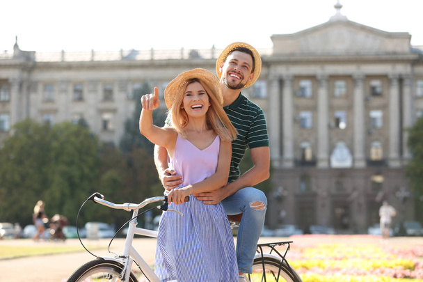 Happy couple with bicycle outdoors on summer day - Фото, изображение