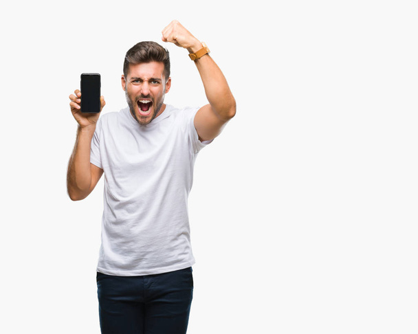 junger gutaussehender Mann zeigt Smartphone-Bildschirm vor isoliertem Hintergrund genervt und frustriert schreiend vor Wut, verrückt und schreiend mit erhobener Hand, Wut-Konzept - Foto, Bild