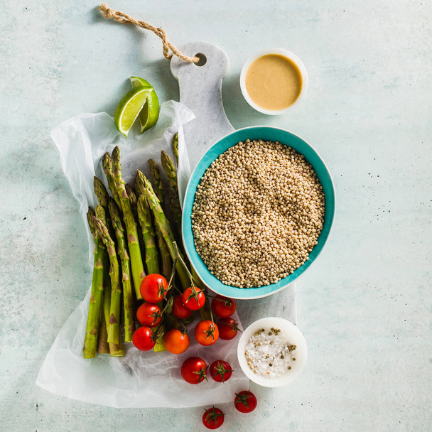 grain Sorghum or great milet with green asparagus and cherry tomatoes on the table. ingredients for gluten-free recipes. healthy cuisine for people with celiac disease - Valokuva, kuva