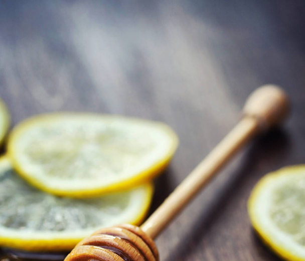 Miel y limón. Palillo de miel y rodajas de limón en rodajas en un woo
 - Foto, Imagen