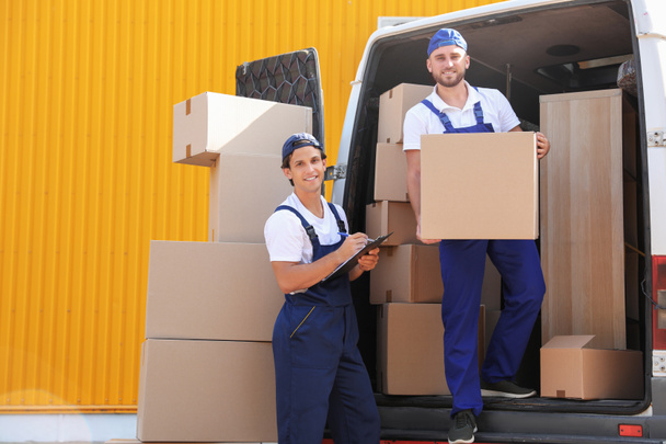 Male movers unloading boxes from van outdoors - Zdjęcie, obraz