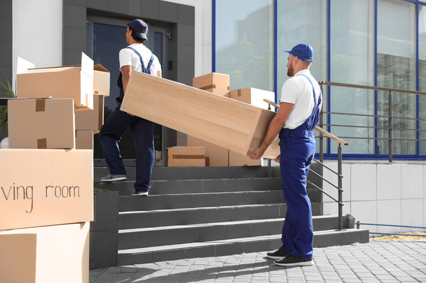 Male movers carrying shelving unit into new house - Foto, Imagem