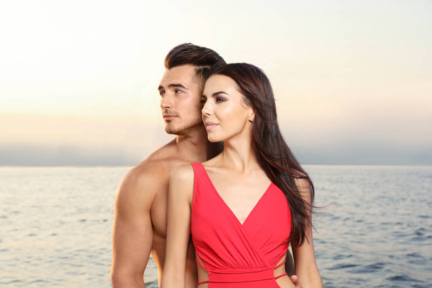 Young man and his beautiful girlfriend in bikini on yacht. Happy couple during sea trip - Фото, зображення