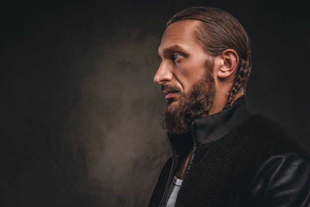 Profile of a fashionable bearded male in a black jacket. Isolated on dark textured background. - Foto, imagen