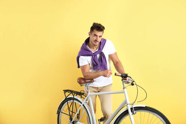 Handsome young hipster man with bicycle on yellow background - Fotografie, Obrázek