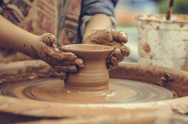 De handen van een pottenbakker. Pottenbakker maken van keramische mok op het aardewerk wiel - Foto, afbeelding