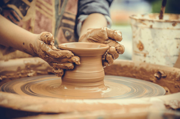 De handen van een pottenbakker. Pottenbakker maken van keramische mok op het aardewerk wiel - Foto, afbeelding