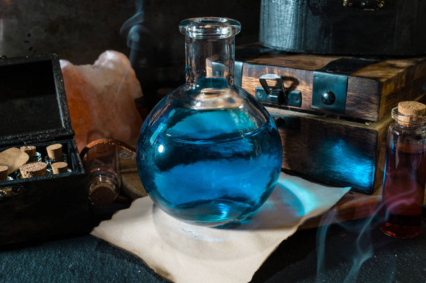Concept magique. Potion bleue en bouteille, bougies, boîte en bois et papier artisanal. Fond magique
 - Photo, image