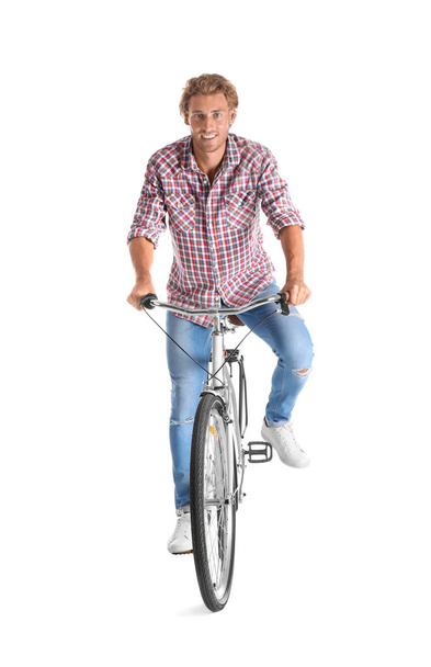Handsome young man riding bicycle on white background - 写真・画像