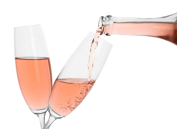 Nalitím růžové šampaňské z láhve do skla na bílém pozadí - Fotografie, Obrázek