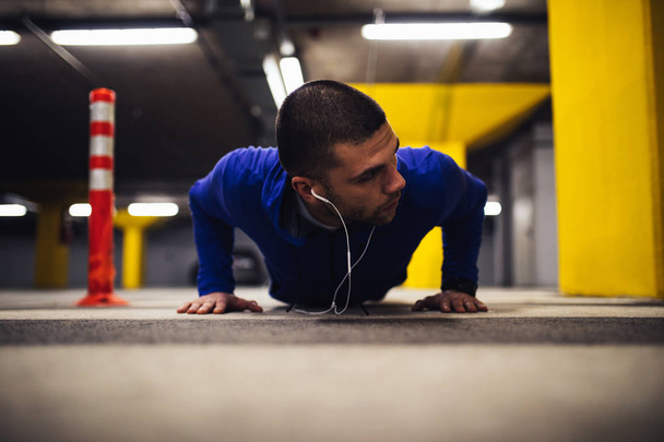 Young man doing pushups indoors - Fotografie, Obrázek