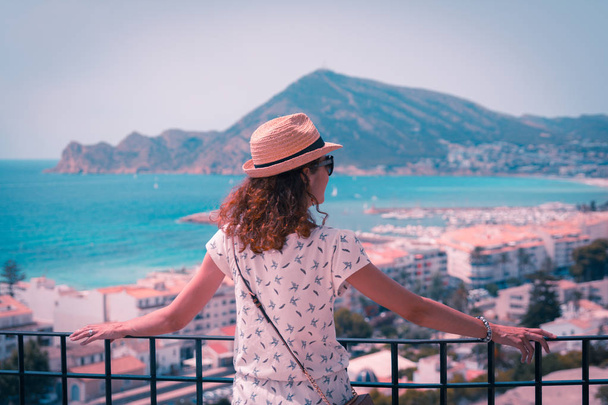 Κυπαρισσί και πορτοκαλί ματιά μιας γυναίκας με άχυρο καπέλο ψάχνετε στη Μεσόγειο θάλασσα σε Altea, Αλικάντε, Ισπανία - Φωτογραφία, εικόνα