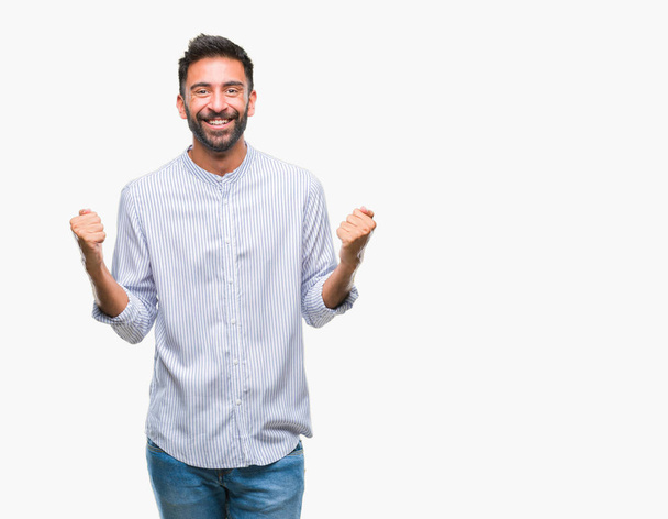 Adult hispanic man over isolated background celebrating surprised and amazed for success with arms raised and open eyes. Winner concept. - Photo, Image